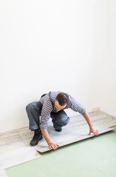 Professional flooring installer placing laminate planks during a home renovation