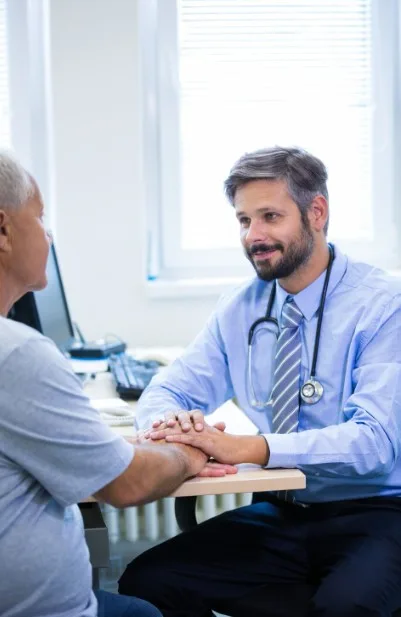 Médico reconfortando a un paciente sosteniendo sus manos durante una consulta
