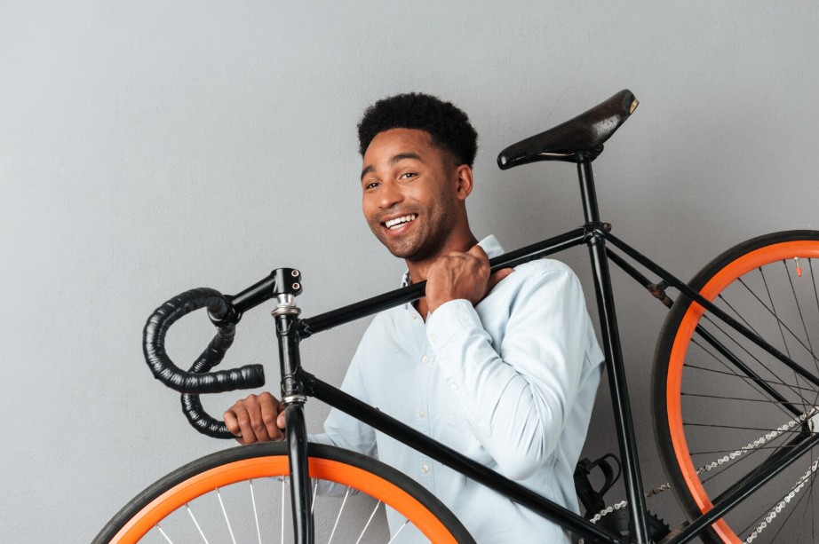 Cliente sonriente cargando una bicicleta nueva sobre el hombro
