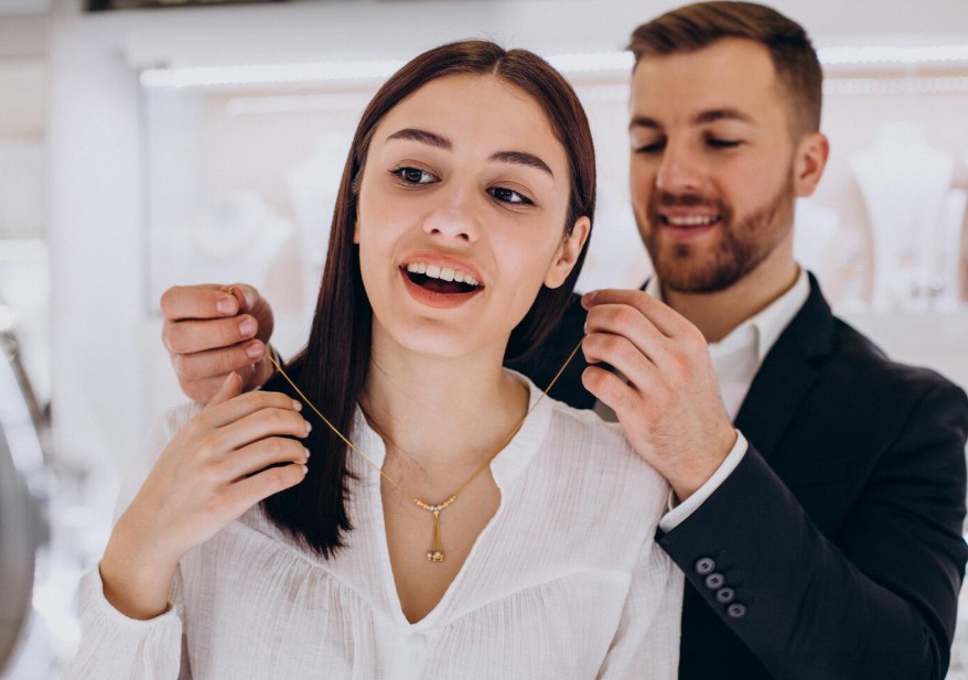Pareja celebrando una compra de joyería mientras le colocan un collar