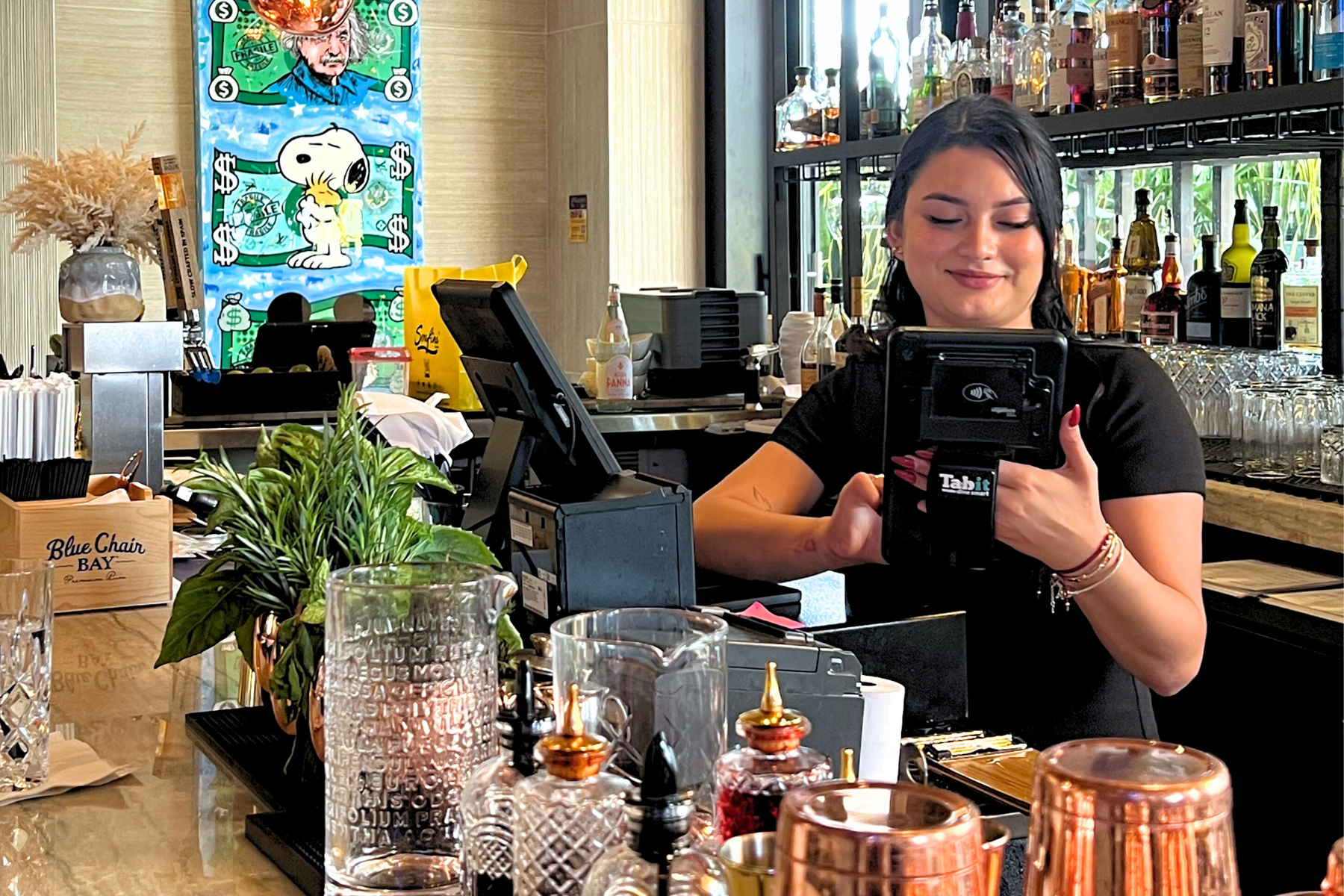 Server using a Tabit handheld payment device at a restaurant bar